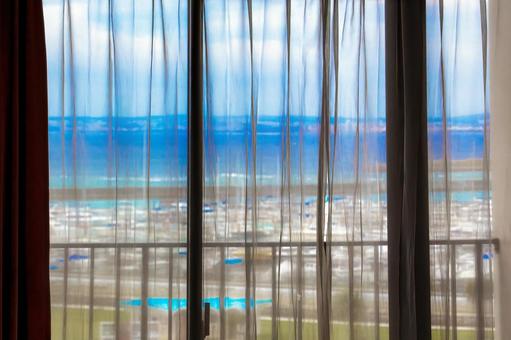 窓から海が見えるカーテン越しの風景 窓から海が見えるカーテン越しの風景の写真