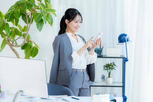 スマホを操作するビジネスウーマン ビジネスウーマン,スマホ,笑顔の写真素材