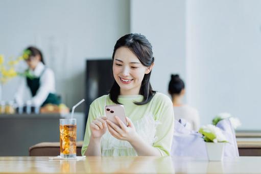 カフェでスマホを使う若い女性 カフェでスマホを使う若い女性 女性,カフェ,笑顔の写真素材