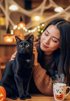ハロウィンの猫カフェで黒猫を撫でる女性 ハロウィンの猫カフェで黒猫を撫でる女性の写真