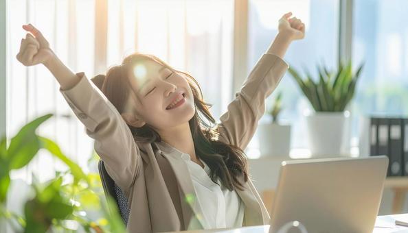 仕事が終わり達成感で背伸びをする社員の写真
