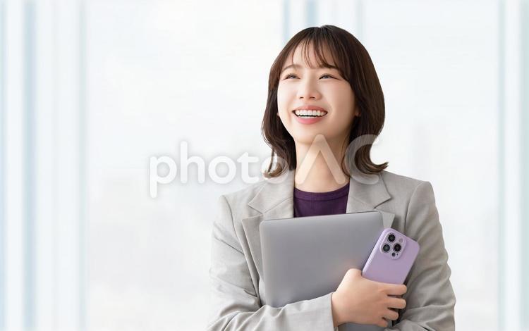 パソコンとスマホを持つ笑顔の女性 女性,ビジネス,笑顔の写真素材