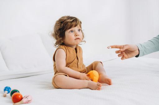 玩具を持ちお座りする子供とクリームがついた指先 玩具を持ちお座りする子供とクリームがついた指先 赤ちゃん,玩具,持つの写真素材