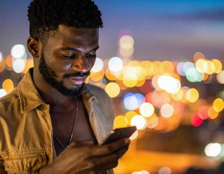 屋上でスマートフォンを操作する若い男性 屋上でスマートフォンを操作する若い男性の写真