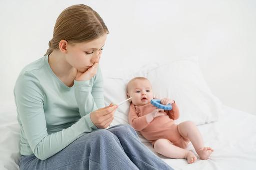 困った顔で体温計を見つめる女性 困った顔で体温計を見つめる女性 親子,体温計,見るの写真素材