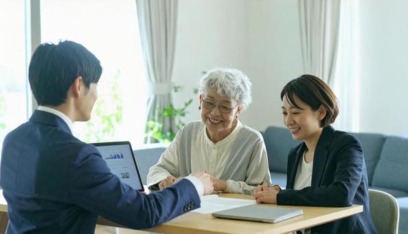 男性営業マンの説明を聞く親子 男性営業マンの説明を聞く親子の写真