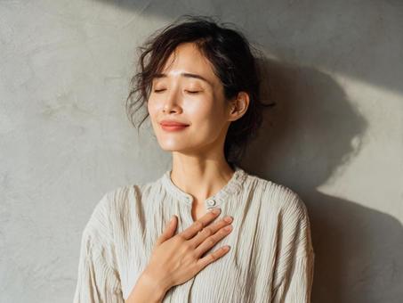 胸に手を当ててほっとする女性の写真