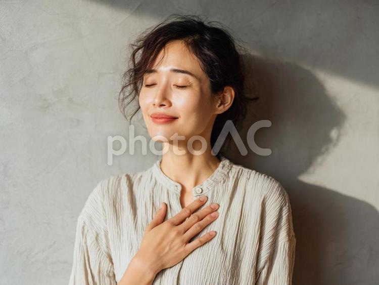 胸に手を当ててほっとする女性 女性,若い,目を閉じるの写真素材