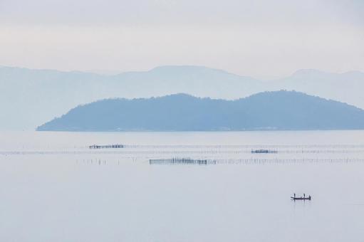 冬の琵琶湖沖に浮かぶ島と魚網と小舟の風景 冬の琵琶湖沖に浮かぶ島と魚網と小舟の風景の写真