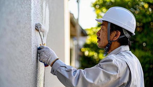住宅の外壁塗装をする作業服の男性 住宅の外壁塗装をする作業服の男性の写真