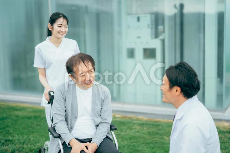 車椅子に乗った患者と医療スタッフ（3人） 車椅子,患者,病院の写真素材