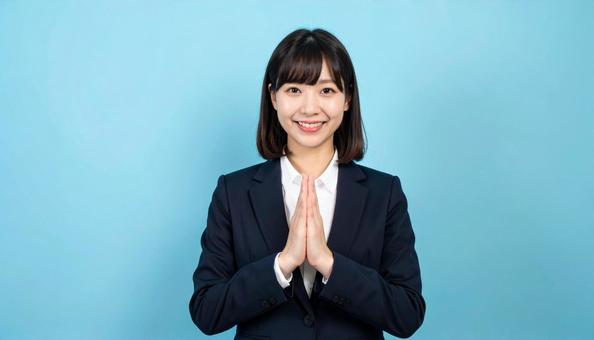両手をあわせお願いするビジネスウーマンの写真