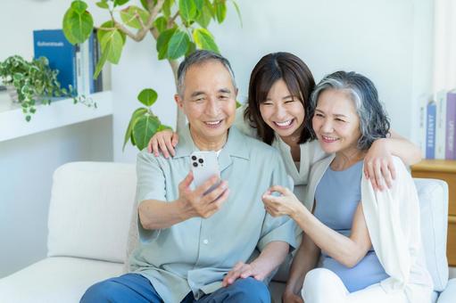 リビングでスマホを見るシニア夫婦と子供 シニア,夫婦,スマホの写真素材