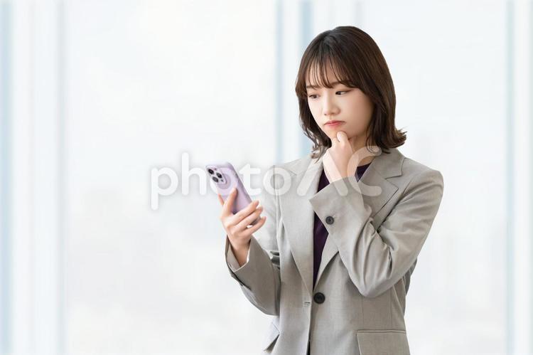 スマホを見て考える女性・ビジネスウーマン 女性,スマホ,困るの写真素材