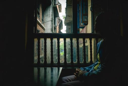 暗いレストランの窓辺から外を見る女性 暗いレストランの窓辺から外を見る女性の写真