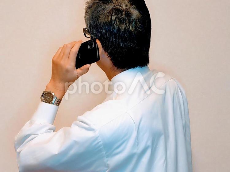携帯電話を使用中のビジネスマン（後ろ姿） 電話,通話,男性の写真素材