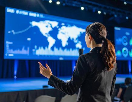 スクリーンの前でプレゼンする女性 スクリーンの前でプレゼンする女性の写真