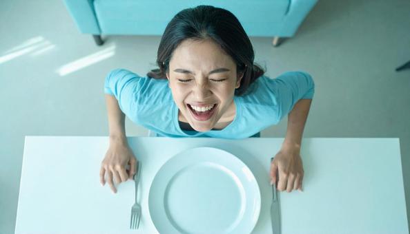 食後、空になったお皿を前に笑顔の女性 食後、空になったお皿を前に笑顔の女性の写真