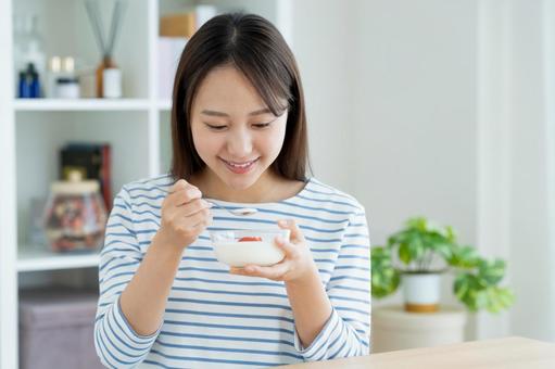 ヨーグルトを食べる若い女性 ヨーグルトを食べる若い女性の写真