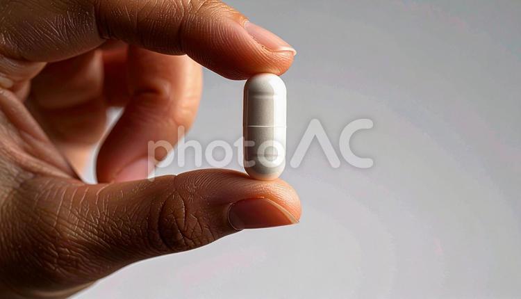 薬一錠を親指と人差し指で持つ手 カプセル,手,医療の写真素材