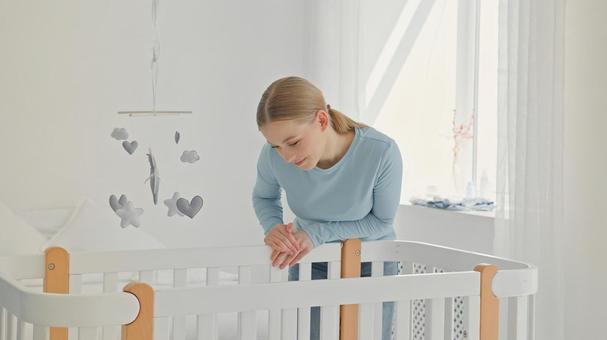 ベビーベッドの中を微笑み覗く女性 ベビーベッドの中を微笑み覗く女性 女性,見る,微笑むの写真素材