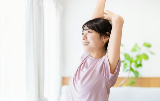 自宅のリビングでストレッチをする女性 自宅のリビングでストレッチをする女性 女性,ストレッチ,柔軟の写真素材