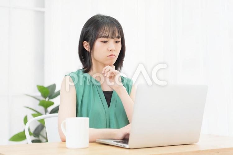 肘をついて考え事をしている若い女性 ノートパソコン,パソコン,女性の写真素材