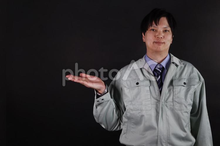 作業服を着た男性が、片手を差し出して説明 作業員,作業服,男性の写真素材