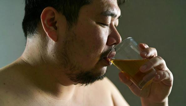 薬を飲む肥満男性 薬を飲む肥満男性の写真