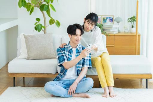 リビングでスマホを見るカップル スマホ,笑顔,カップルの写真素材