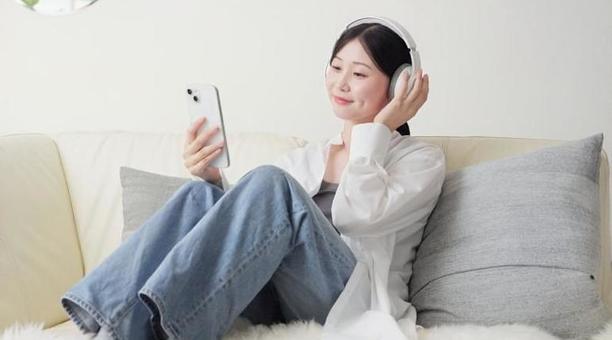 ワイヤレスヘッドフォンで音楽を聞く女性 ワイヤレスヘッドフォンで音楽を聞く女性の写真