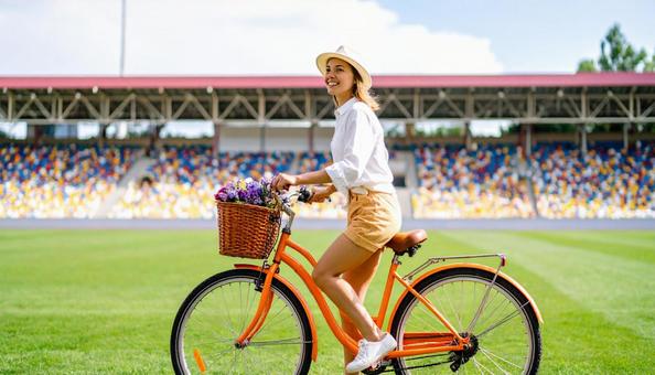 観客席の前を自転車に乗る帽子を被った女性 観客席の前を自転車に乗る帽子を被った女性の写真