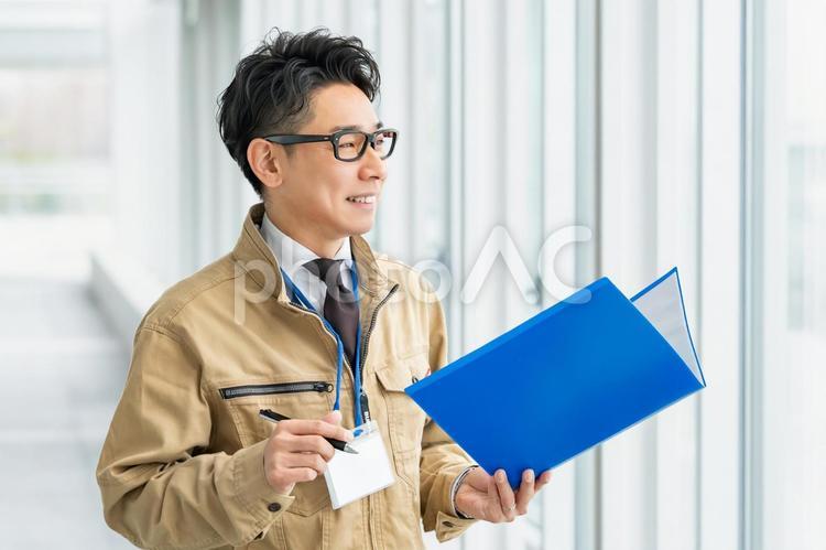 笑いながら外を確認する作業服の男性 ビジネス,ビジネスマン,作業員の写真素材
