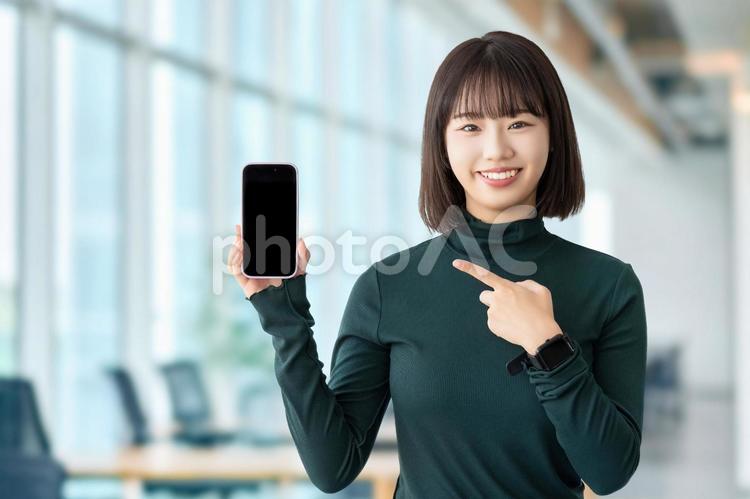 スマホを指差す女性・ビジネスウーマン 女性,スマホ,案内の写真素材