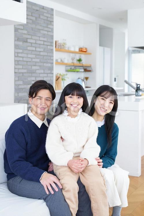 ソファーに座ってカメラ目線で記念撮影する家族 家族,男性,女の子の写真素材