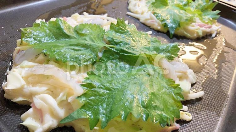 シソをのせて焼き始める家庭のお好み焼き お好み焼き,シソ,粉物の写真素材