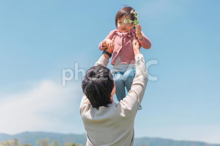 公園で野花を持ってパパと遊ぶ女の子 子供,青空,親子の写真素材