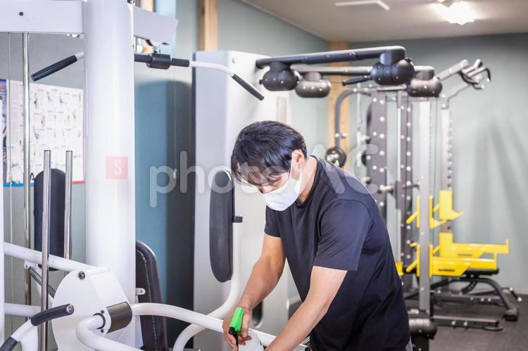 スポーツジムでマシンを消毒する男性 消毒,アルコール消毒,スポーツジムの写真素材
