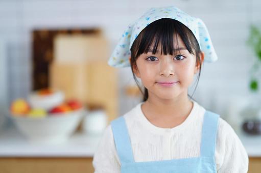 料理を楽しむ笑顔のエプロン姿の女の子の写真
