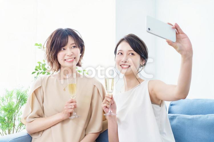 シャンパングラスを手に撮影する女性2人  女子会,ホームパーティー,記念写真の写真素材
