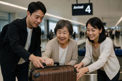 到着ゲートで荷物を受け取る夫婦と母親 到着ゲートで荷物を受け取る夫婦と母親の写真