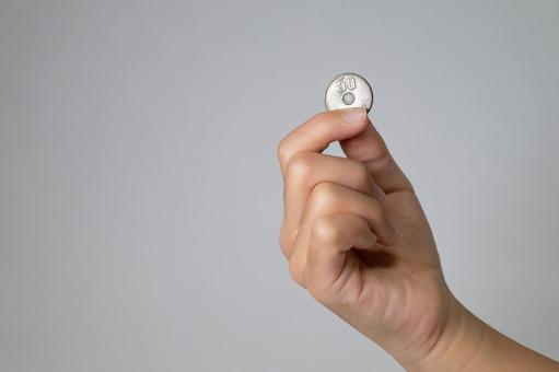 50円硬貨を指先でつまむ子供の手 50円玉,硬貨,日本円の写真素材