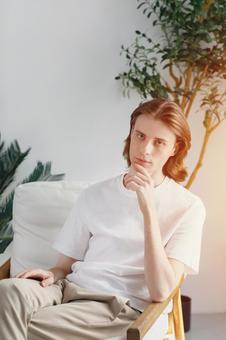 ソファに座って顎に手をやるカメラ目線の男性 男性,外国人,欧米人の写真素材