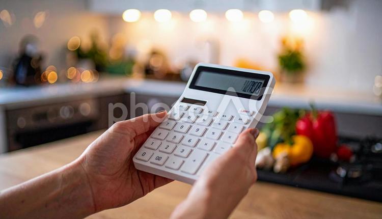 光熱費イメージ　台所で電卓を手に取る手 電卓,食費,光熱費の写真素材