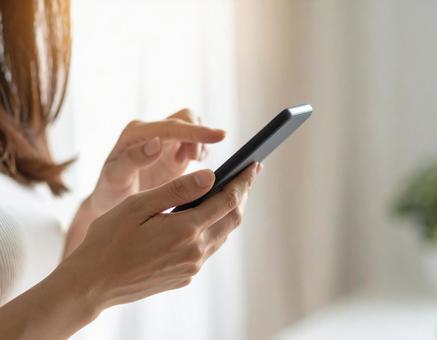 スマホを操作する女性の手元 スマホを操作する女性の手元の写真