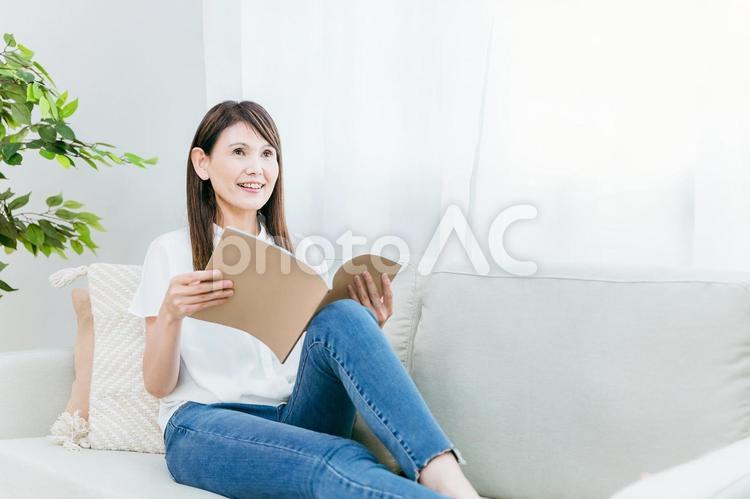 ソファに座るミドル世代の女性（ノート） 勉強,本,資格の写真素材