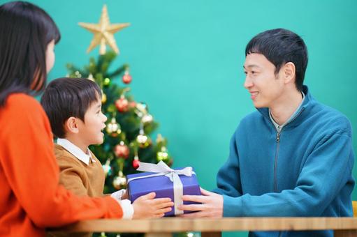 男性が男の子にプレゼントを渡す様子 男性が男の子にプレゼントを渡す様子の写真