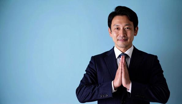 両手をあわせてお願いしているビジネスマンの写真