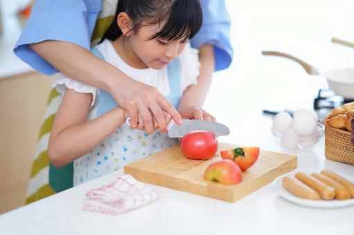 料理を手伝う子どもと見守る大人の姿 女の子,トマト,野菜の写真素材