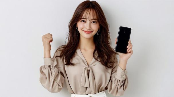 スマホを手に笑顔でガッツポーズする女性 スマホを手に笑顔でガッツポーズする女性の写真